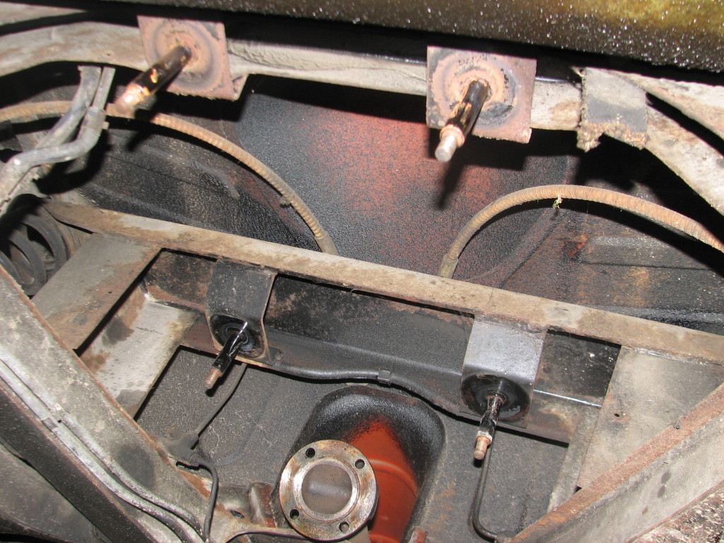 Photo of the four differential mounts while the differential is removed.  The ones in the top portion of the photograph are towards the rear of the car.  The lower ones are towards the front of the car.  The front mount on the passenger's side (the American passenger's side, that is) of the car is generally the one that goes first.  The cracks can be either visible on the bottom radiating out from the center or on top next to the body where they are hard to see.  To be clear, these are not cracked... just showing what the mounts look like.
