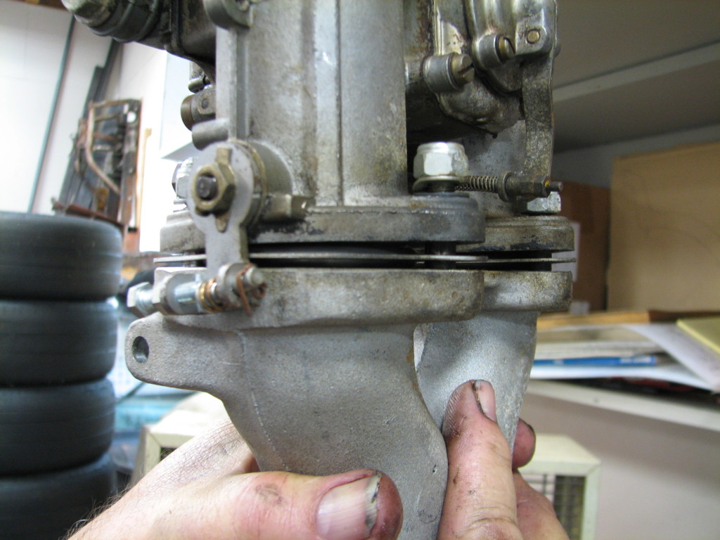 This photo shows Dean holding one of the carbs in the air as it is mounted on the intake.  He took the intake off the motor and left the carb just like it was.  His hand is holding the intake.  You can see looking at the junction where the carb and it's rubber gasket meet the intake that there is a gap.  There is not supposed to be a gap.  The gap is allowing extra air in, which will cause a lean condition.  Dean saw other indications that this motor was running very hot, and the lean condition suffered by the cylinders fed by this carburetor would only make that (running hot) worse.
